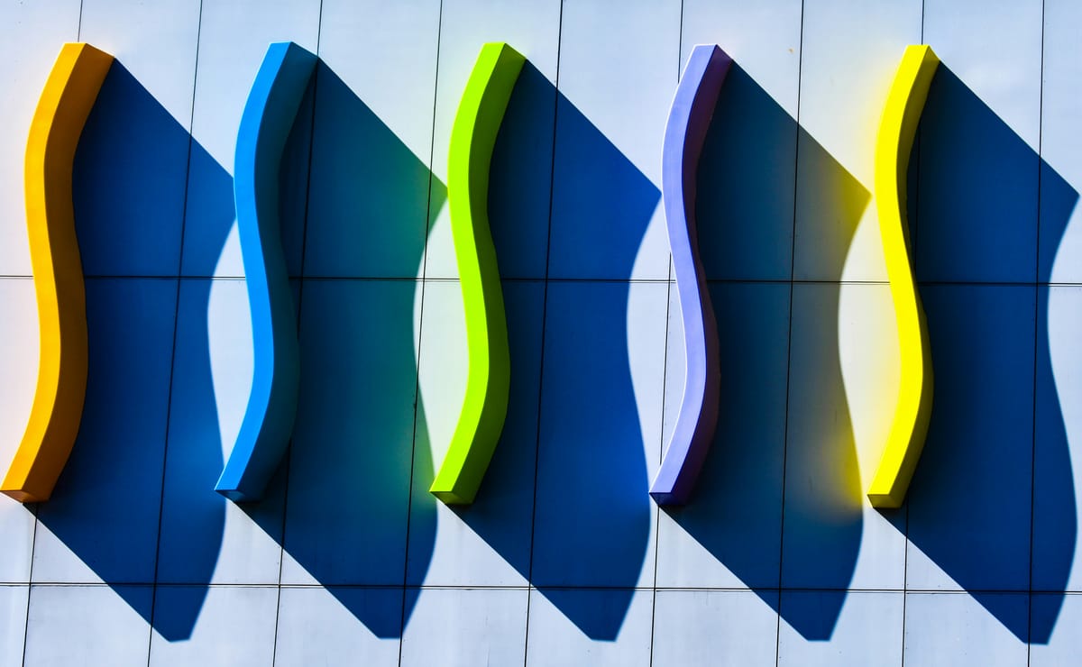 5 multicoloured S shapes on the side of a building casting shadows. 